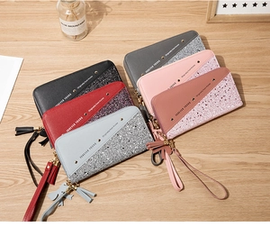 Flat lay of multiple long zip wallets with color-matching glitter and tassels on wood