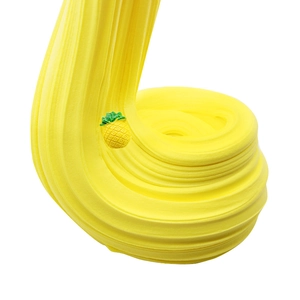 Close-up of stretchy yellow butter slime texture with a tiny pineapple decoration