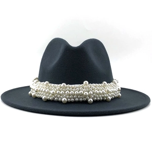 Detailed macro view of white faux pearl band on elegant black wide brim wool fedora hat