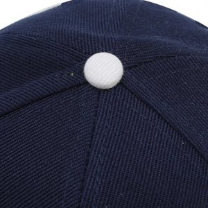 Gros plan de la couronne d'une casquette bleu marine avec bouton blanc et coutures soignées