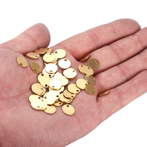 Hand holding a set of polished gold round stainless steel pendants for DIY jewelry making