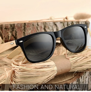 Close-up of bamboo wood arms on classic black frame sunglasses over a rustic straw backdrop