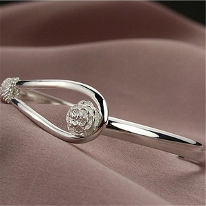 Elegant silver rose flower open cuff bracelet on pink satin background with mirror finish