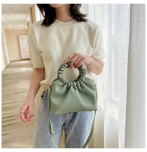 Fashionable light green pleated handbag with ring handle shown on a model in bright room