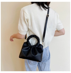 Detail of black pleated cloud bag with stylish ruched round handle and PU leather texture