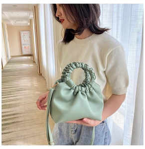 Detail of light green pleated cloud bag featuring soft faux leather and wavy top handle
