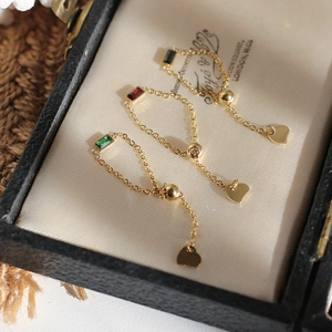 Macro shot of adjustable gold chain rings with emerald, ruby, and black zircon gemstones
