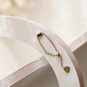 Detail of adjustable gold chain ring with black rectangular stone and heart charm