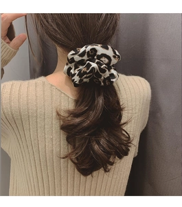 Detail of satin leopard print hair scrunchie worn on a ponytail with elegant pleats