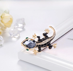 Detailed close-up of a lizard brooch with black enamel, crystals and grey gemstone