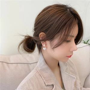 Elegant heart-shaped pearl earrings with gold accents worn by a model in soft lighting