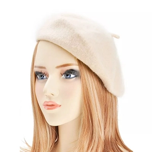 Detail of the knit texture and top accent on a minimalist cream-colored wool beret