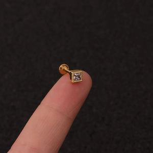 Macro detail of tiny gold stud piercing with square zircon and flat back base