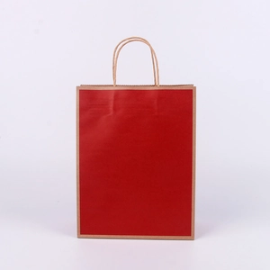 Detail view of a plain red kraft paper bag with brown twisted rope handles and clean edges