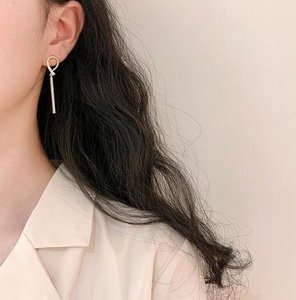 Close-up of elegant long gold geometric drop earrings worn by a model on plain background