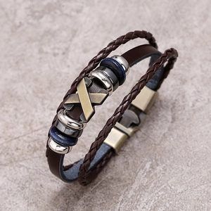 Close-up of multilayer leather bracelet with X-shaped metal charm and beaded details