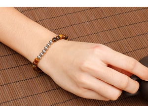 Detailed view of tiger eye bead bracelet with silver metal accents on a bamboo mat