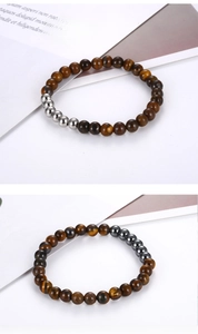 Detail of tiger eye bead bracelet with silver and dark grey metal accents on white background