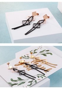 Détail de boucles d'oreilles géométriques avec clous carrés et pompons en chaîne serpent