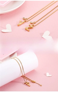 Close-up of golden fine steel alphabet necklace with a small white crystal pendant