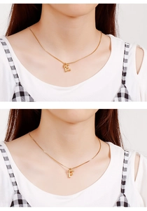Detail of gold letter pendants E and F with bamboo texture and cubic zirconia stone