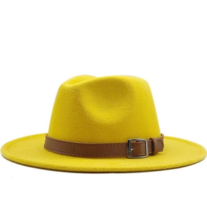 Detail of yellow wool fedora hat featuring a brown leather band and silver buckle accent