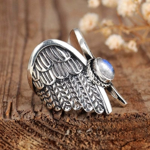 Vintage silver angel wing ring with round moonstone on a rustic wood background