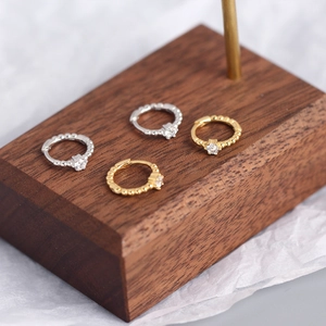 Macro shot of gold and silver beaded hoop earrings with cubic zirconia on wood
