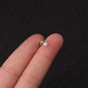Close-up of a silver star stud earring with a clear gemstone held on a fingertip