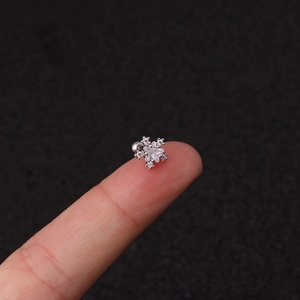 Detailed view of a silver snowflake stud earring with clear crystals on a fingertip