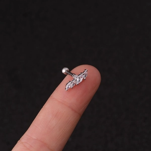 Macro shot of a silver stainless steel piercing earring with sparkling zircon on a fingertip
