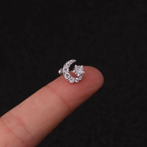 Macro shot of tiny silver star and moon cartilage studs with clear cubic zirconia