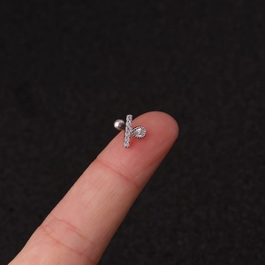 Macro shot of a silver T-shaped stud earring with a crystal drop pendant on a fingertip