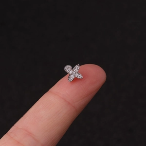Close-up of a silver floral helix stud earring with cubic zirconia on a fingertip