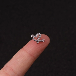 Sparkling silver heart and keyhole stud earring with pavé stones shown on fingertips