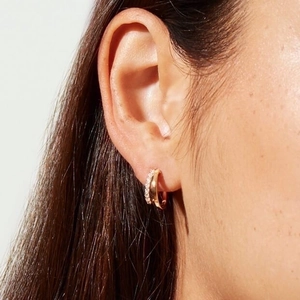Elegant gold double hoop earrings with sparkling crystal accents worn by a model