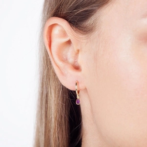 Fashionable gold hoop earrings with purple teardrop zircon pendant shown on model