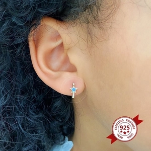Close-up of blue enamel star hoop earring in 925 sterling silver worn on ear