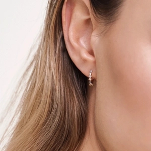 Elegant gold huggie earrings with clear cubic zirconia on a female model