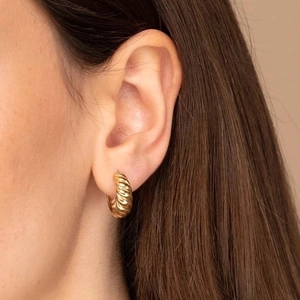 Minimalist golden croissant hoop earrings with elegant twisted texture worn by model