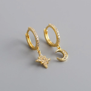 Macro shot of asymmetric gold star and moon earrings with sparkling micro-pave zircons
