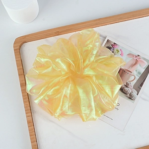 Detail of yellow iridescent organza scrunchie on marble tray with artistic background