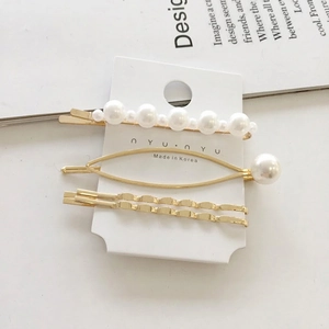 Detailed view of a 3-piece Korean pearl hair clip set in gold finish on a display card