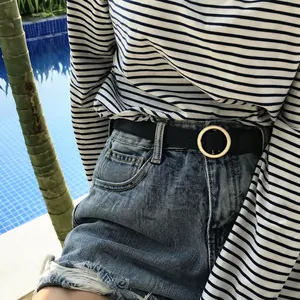 Slim black leather belt with silver circular buckle worn on casual denim shorts