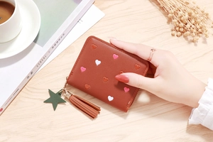 Short brown PU leather wallet for women with heart embroidery and tassel on wooden table