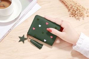 Close-up of a dark green wallet with heart embroidery and a gold star tassel charm