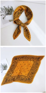 Detail of yellow pleated square scarf featuring black sun totem print and silky texture