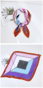 Detail of pleated silk scarf showing colorful geometric blocks and silver chain patterns