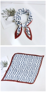 Detailed view of pleated blue wave pattern silk scarf with dark red edges