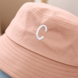 Gros plan sur le chapeau bob rose clair avec broderie du lettrage C et surpiqûres